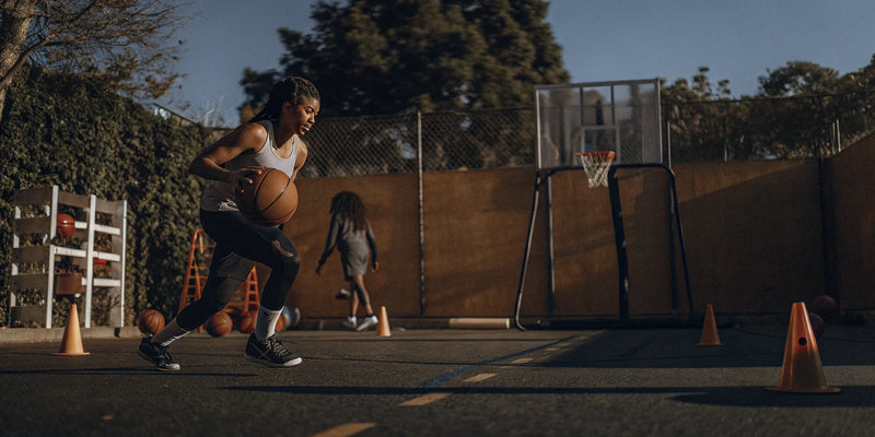 Youth basketball training equipment: cones, hoop, and ball.