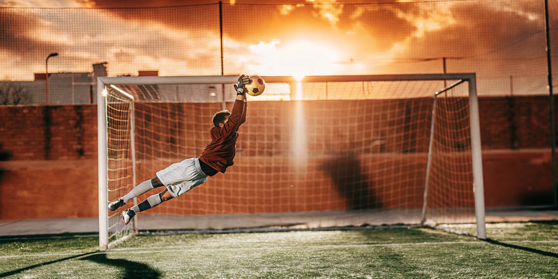 Goalkeeper deflecting a soccer ball during training.