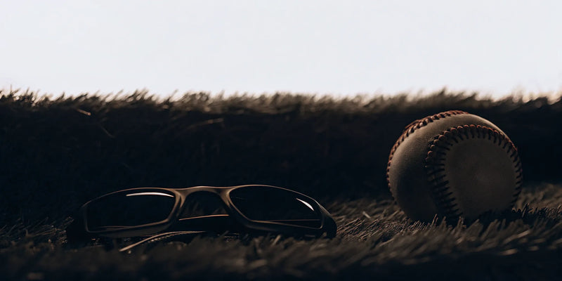 Baseball and vision training sunglasses on turf, some of the best coaching tools to buy.