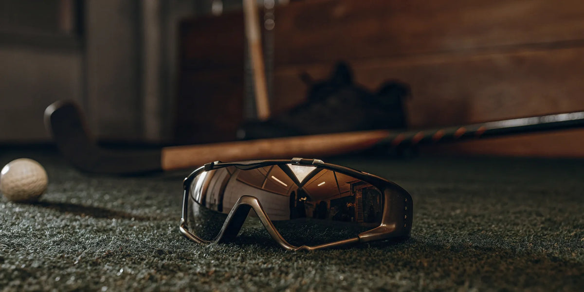 Protective field hockey eye gear on a turf field with a stick and ball.